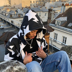 Man wearing black and white star-patterned hoodie on rooftop, urban cityscape background