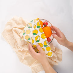 Lemon print reusable food wrap covering bowl of oranges and tomatoes, eco-friendly kitchen gift