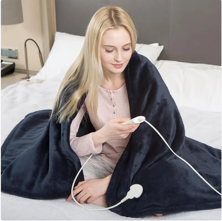 Woman using cozy heated blanket on bed, soft plush electric blanket for comfort