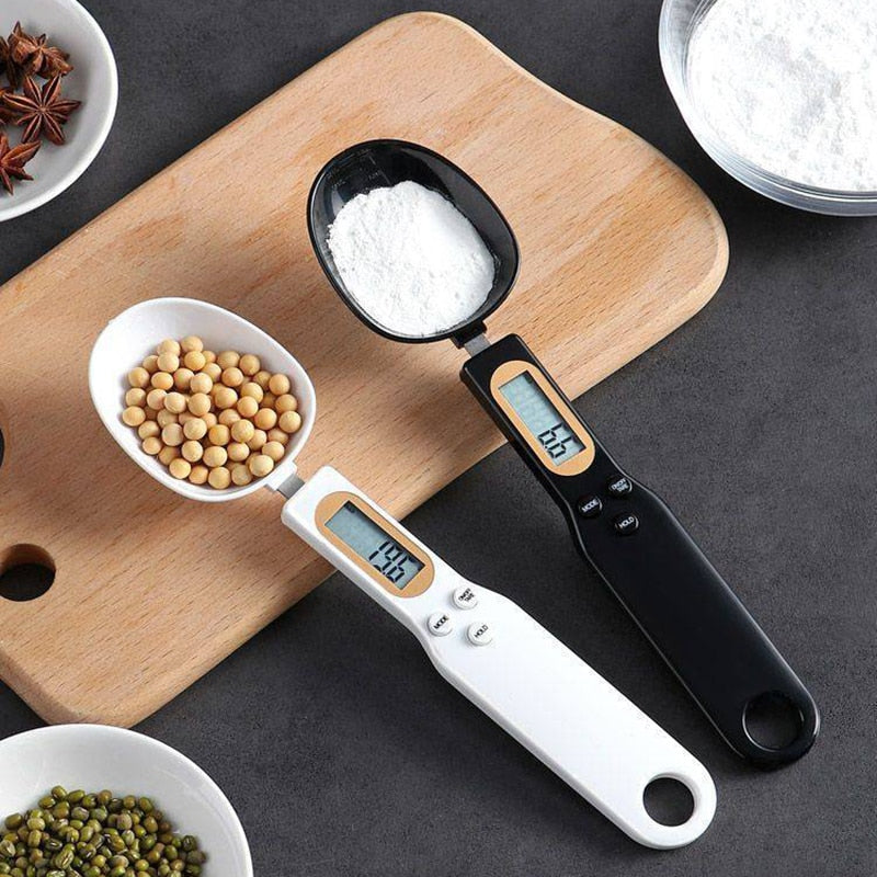 Digital kitchen measuring spoons with LCD display, measuring flour and beans on wooden board
