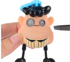 Funny squishy stress toy with spiral eyes, black hair, and striped shirt, held in hand for sensory play