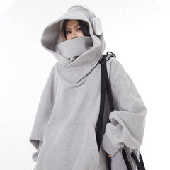 Gray oversized hoodie with high neck and hood, worn with headphones and backpack, cozy streetwear style