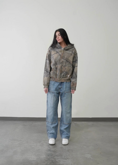 Woman wearing camouflage zip-up hoodie, wide-leg jeans, and white sneakers for casual style