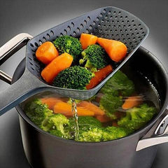 Black slotted spoon lifting steamed broccoli and carrots from pot