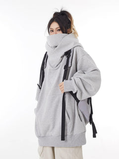 Gray oversized hoodie with hood up, worn with backpack, casual streetwear style