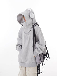 Gray oversized hoodie with hood up, white headphones, and backpack, casual streetwear style
