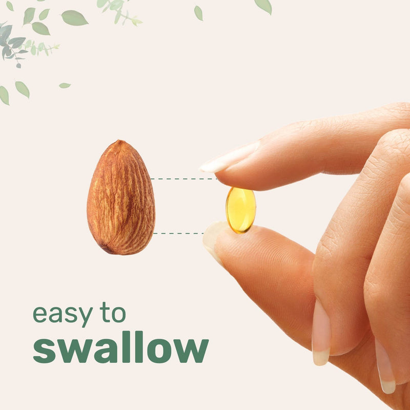 Small easy-to-swallow vitamin capsule held next to almond for size comparison, natural health supplement