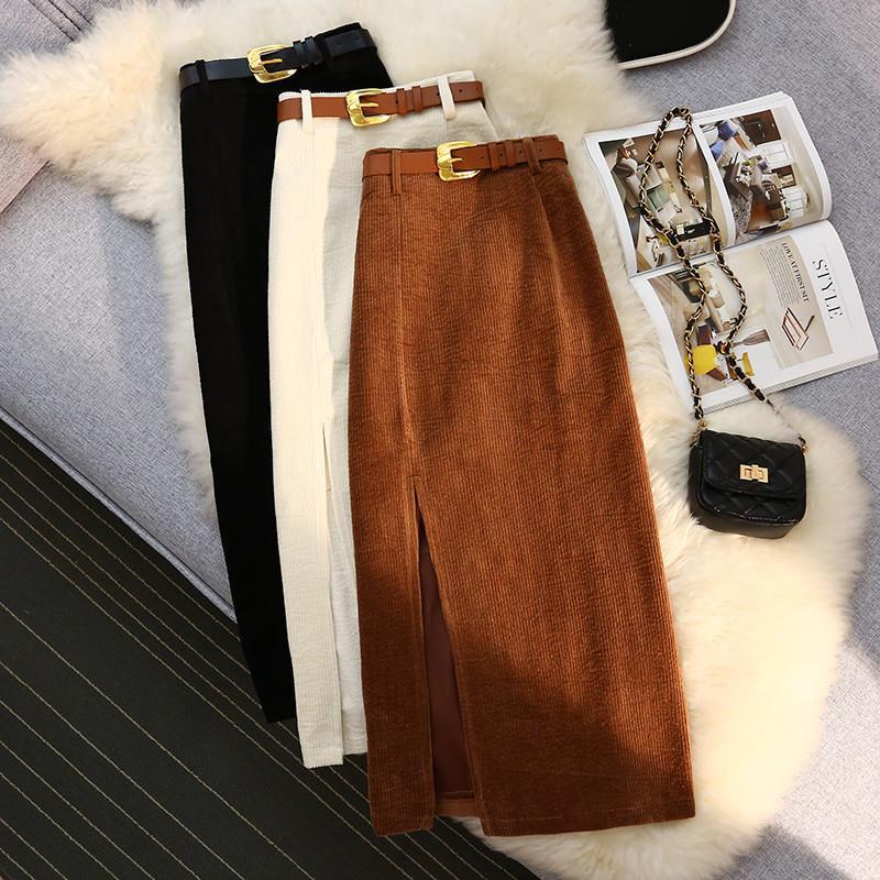 Corduroy pencil skirts with belts in black, cream, and brown, styled with a chic handbag on a fluffy rug.