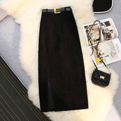 Black corduroy midi skirt with front slit, gold buckle belt, and quilted chain bag on faux fur