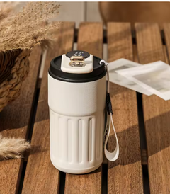 White insulated travel mug with digital temp display, USB port, and strap on wooden table