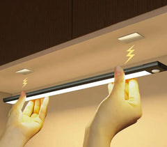 Hands installing sleek under-cabinet LED light strip with motion sensor for kitchen lighting