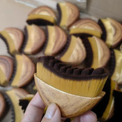 Hand holding wooden brush with natural bristles, ideal for grooming and gift giving