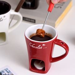 Red chocolate fondue mug with marshmallow being dipped, cozy dessert setup