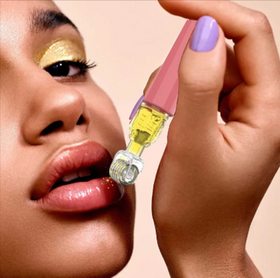 Lip oil applicator with rollerball, golden eye makeup, purple nails, beauty product close-up