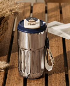 Stainless steel insulated coffee tumbler with digital temp display, blue lid, and carry strap on wooden table