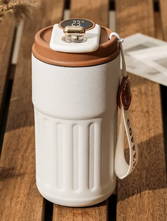 White smart travel mug with digital temp display, brown lid, and carry strap on wooden table