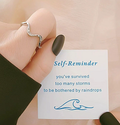 Silver wave ring with crystals, held beside self-reminder card for emotional support gifts
